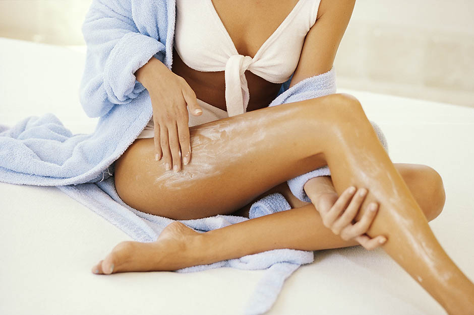WOMAN APPLYING LOTION TO LEGS, CLOSE UP